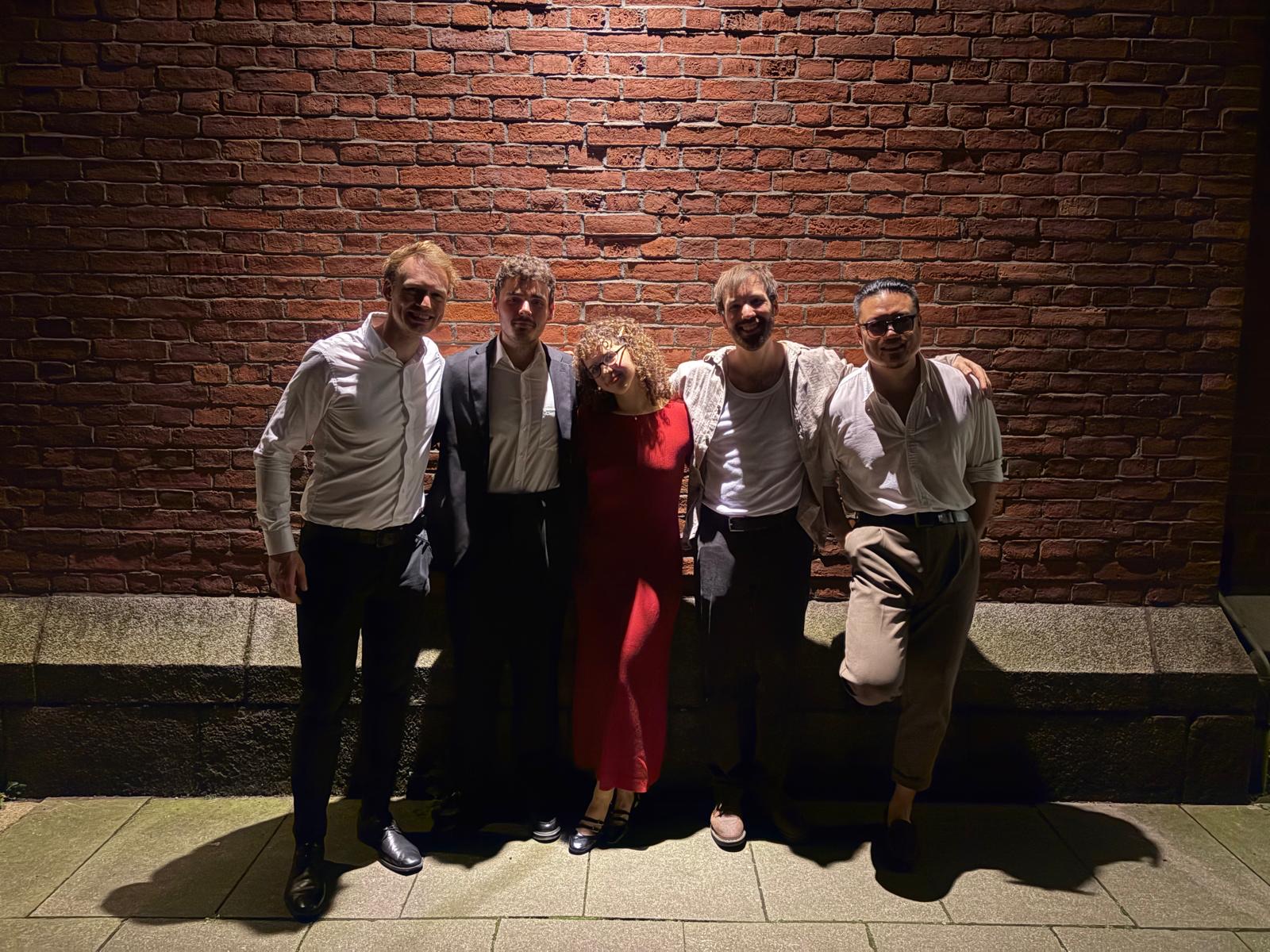 Fünfköpfige Band vor einer Backsteinmauer bei Nacht
