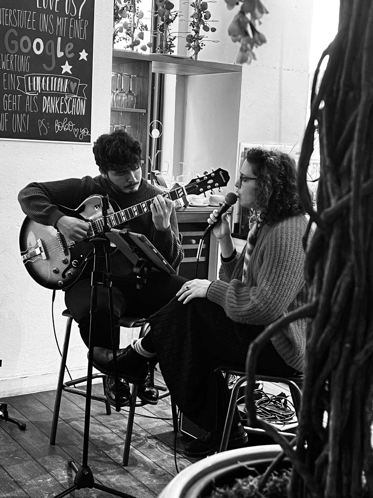 Duo mit Gesang und Gitarre in einem Café, schwarz-weiß