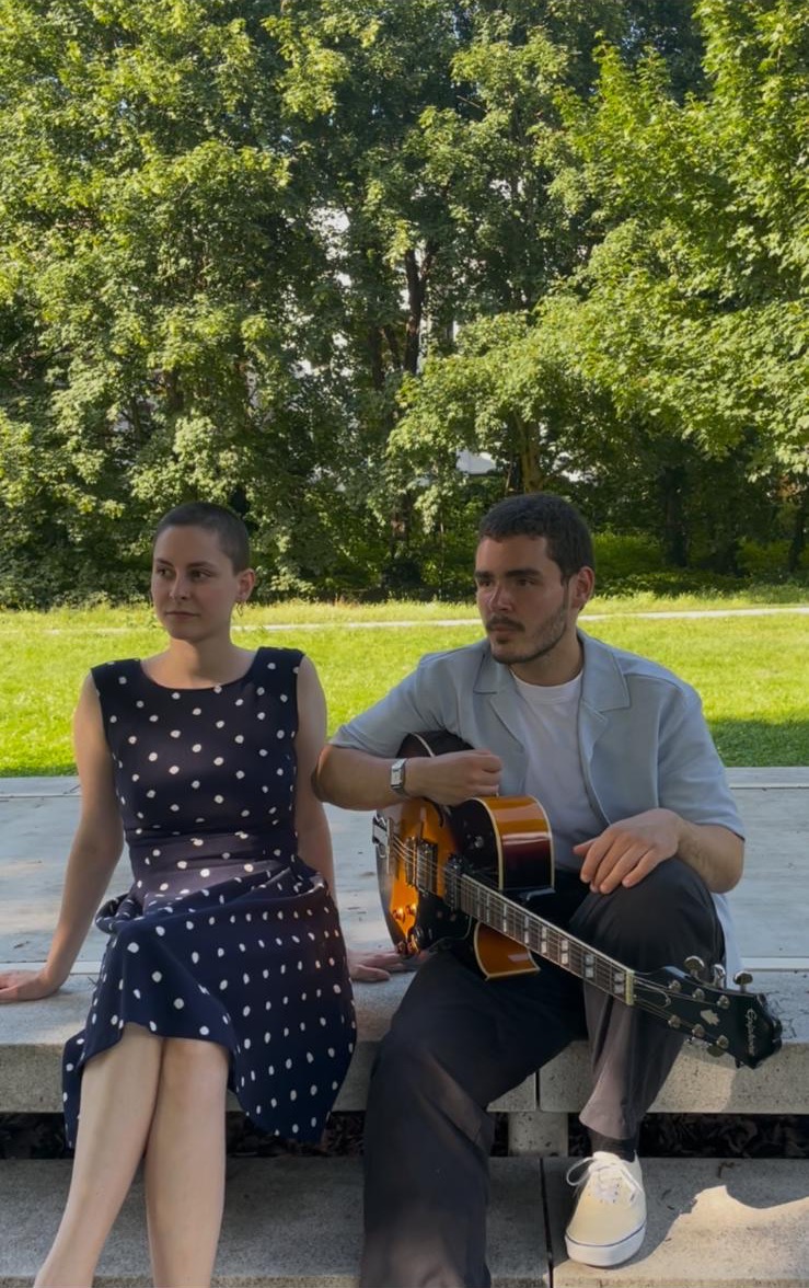 Duo mit Gitarre auf einer Bank im Park