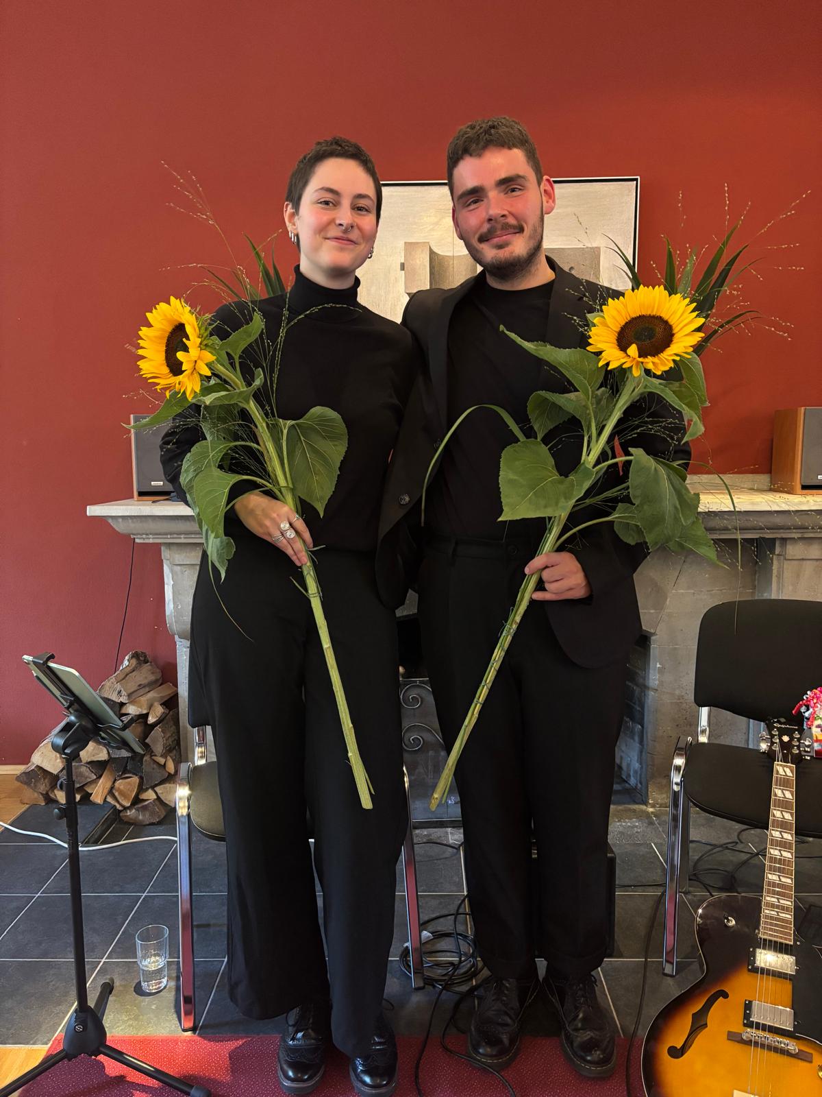 Duo mit Sonnenblumen nach einem Konzert vor roter Wand